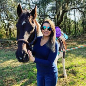 A woman standing next to a horse in the grass