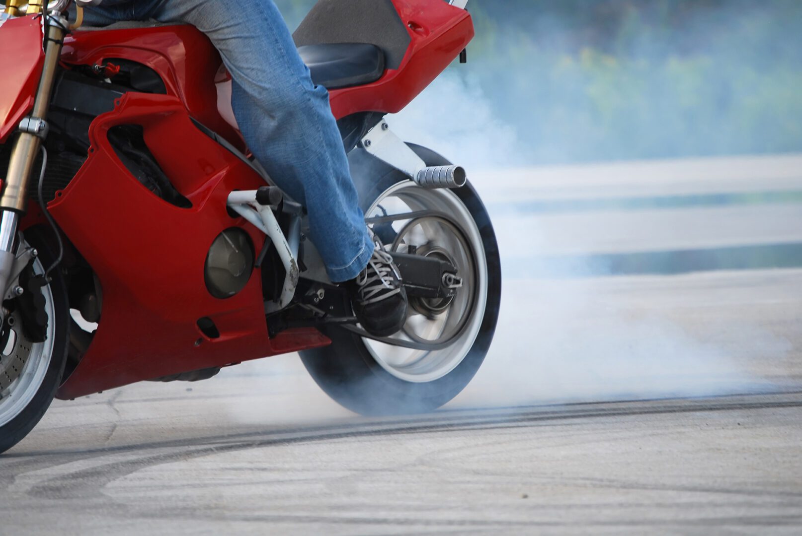 A person riding on the back of a red motorcycle.