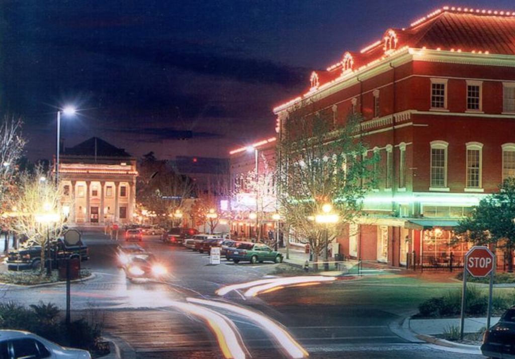 A city street with cars driving down it at night.