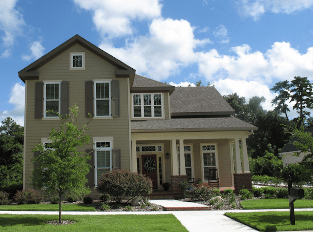 A large house with a lot of green grass on the front lawn.