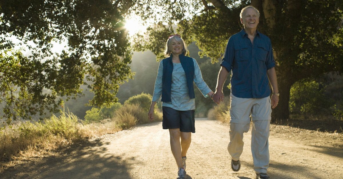 A man and woman holding hands while walking down the road.