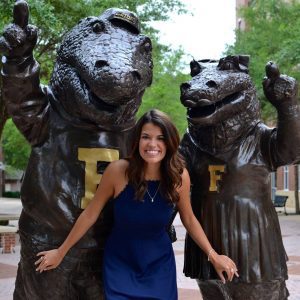 A woman standing next to two large statues of bears.