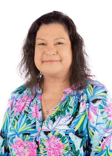 A woman in floral shirt smiling for the camera.